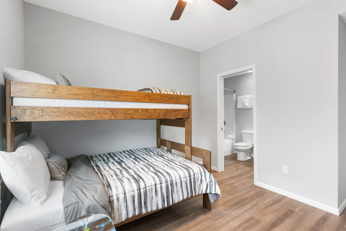 A charming bunk room featuring a sturdy bunk bed with striped bedding and wooden furniture. The space feels playful yet cozy, perfectly suited for children or younger guests to enjoy sleepovers and quiet moments.