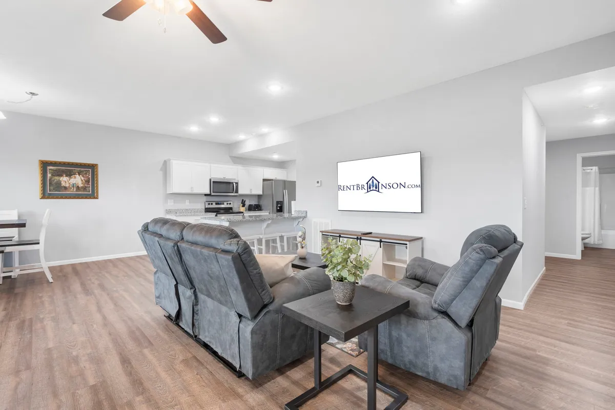 A cozy living room scene with a comfortable sofa facing a television, adjacent to a dining area, with plenty of space for relaxing, watching movies, or enjoying meals together.