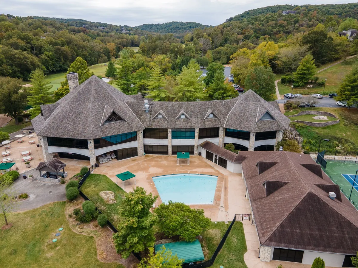 An inviting swimming pool anchors a landscaped garden with unique architecture in the background and natural surroundings. The setting suggests relaxation and a wide range of amenities available after a day of golf.