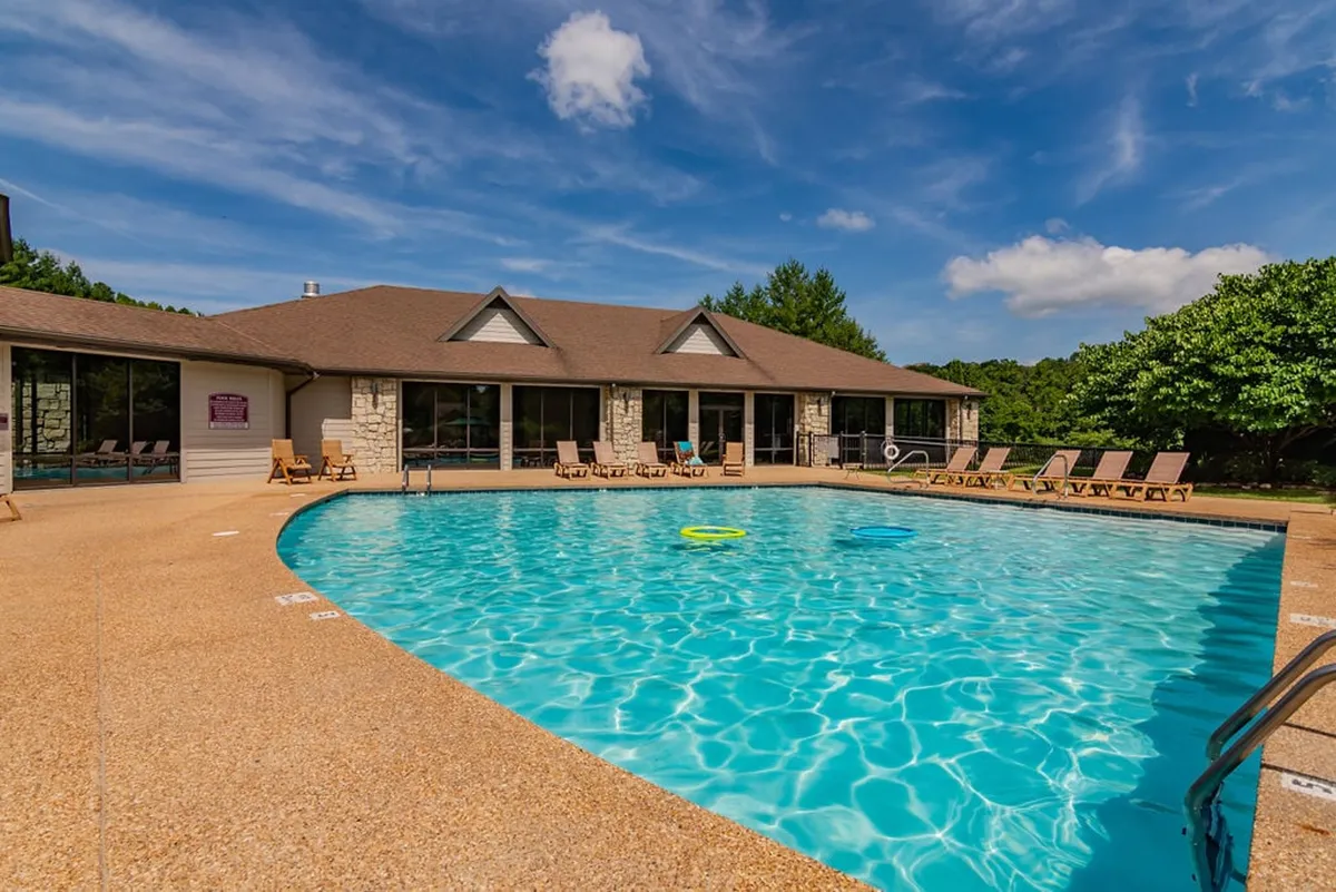 A focused exterior view of a sparkling outdoor swimming pool surrounded by comfortable lounge chairs and lush greenery. The setting reflects relaxation and social fun, ideal for families and guests seeking sunny summer days by the pool.