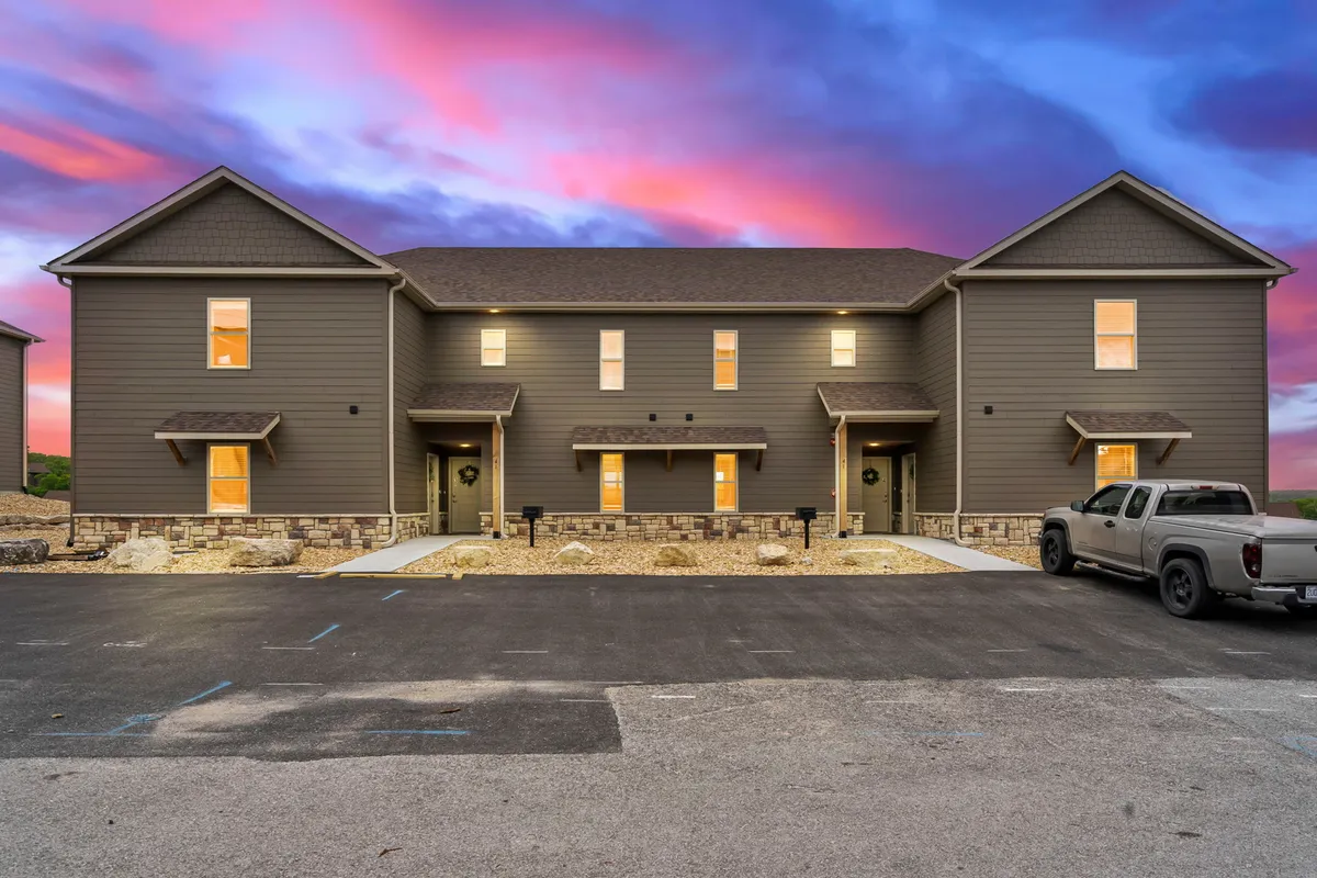 An exterior view of a modern building at sunset, with warmly illuminated windows that suggest a lively and welcoming atmosphere indoors. The colorful sky and glowing lights evoke a sense of both relaxation and anticipation for enjoyable evenings ahead.