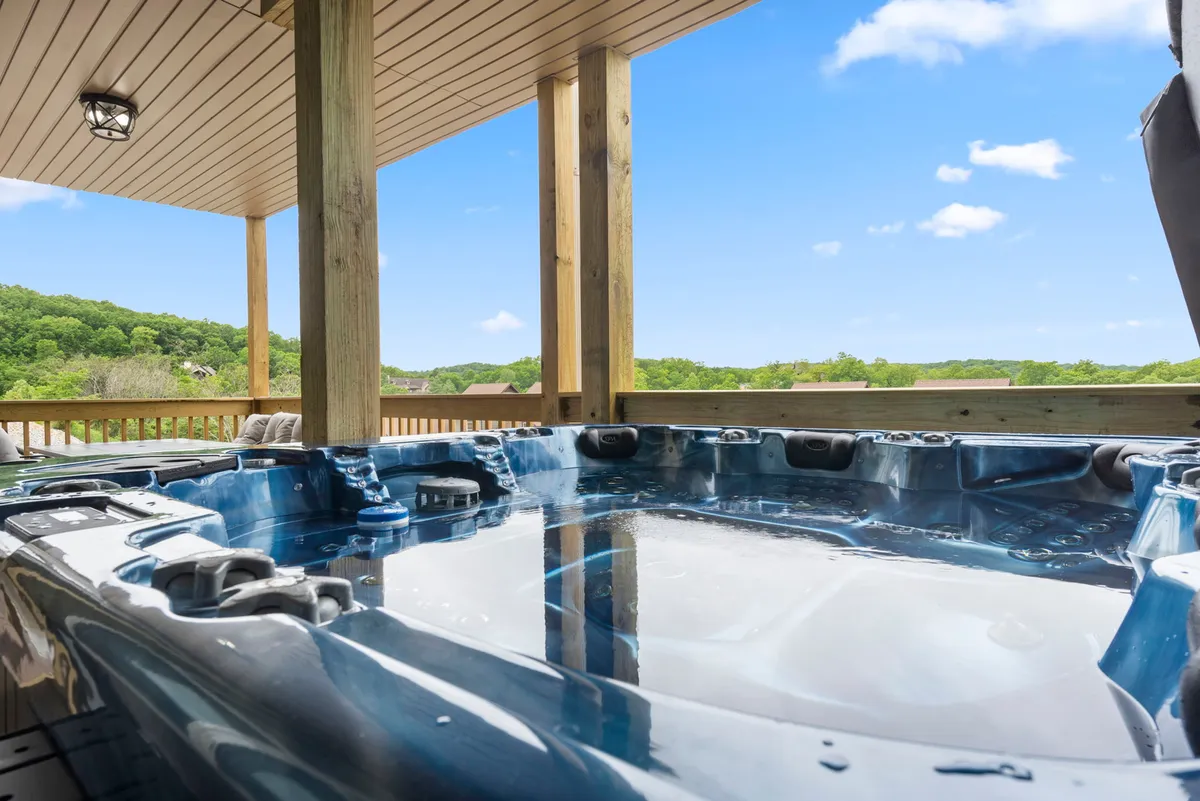 The image shows the exterior wooden deck of the condo at sunset, featuring a private hot tub surrounded by lush greenery and tranquil views. The setting suggests a relaxing and inviting atmosphere, ideal for unwinding after a day at nearby attractions.